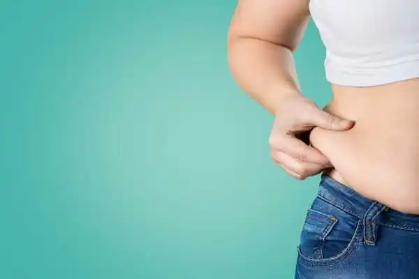 Image of woman pinching her love handles to show weight gain West Bromwich