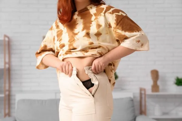 Image of woman trying to do her trousers up after pregnancy weight gain West Bromwich